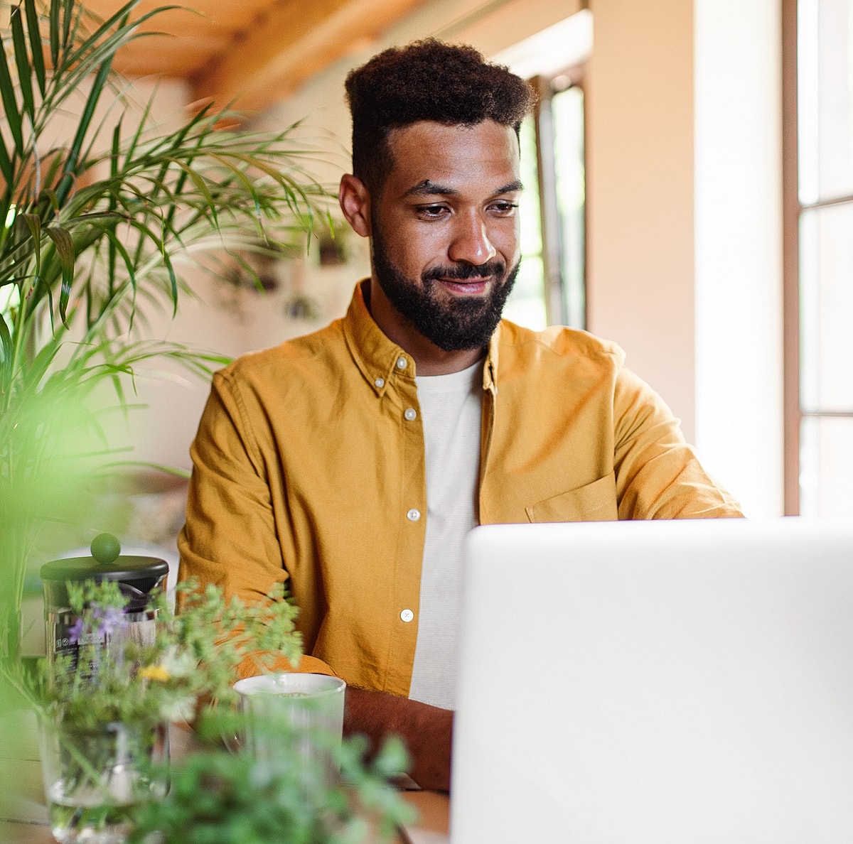 Man using laptop in a bright, green setting.