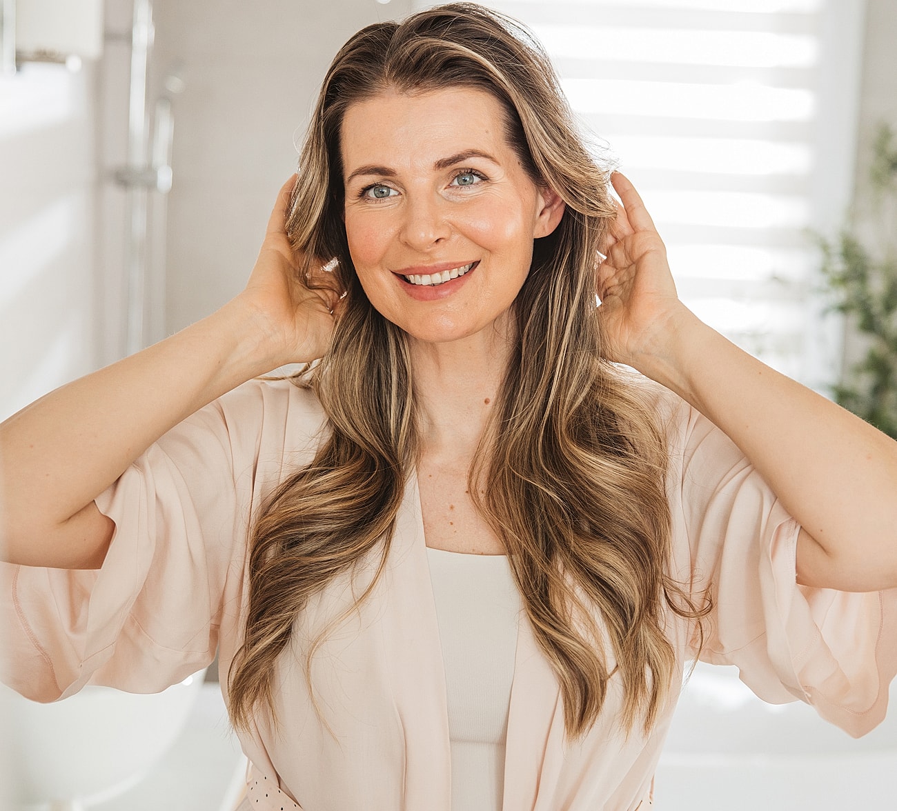Smiling woman adjusting her hair indoors.