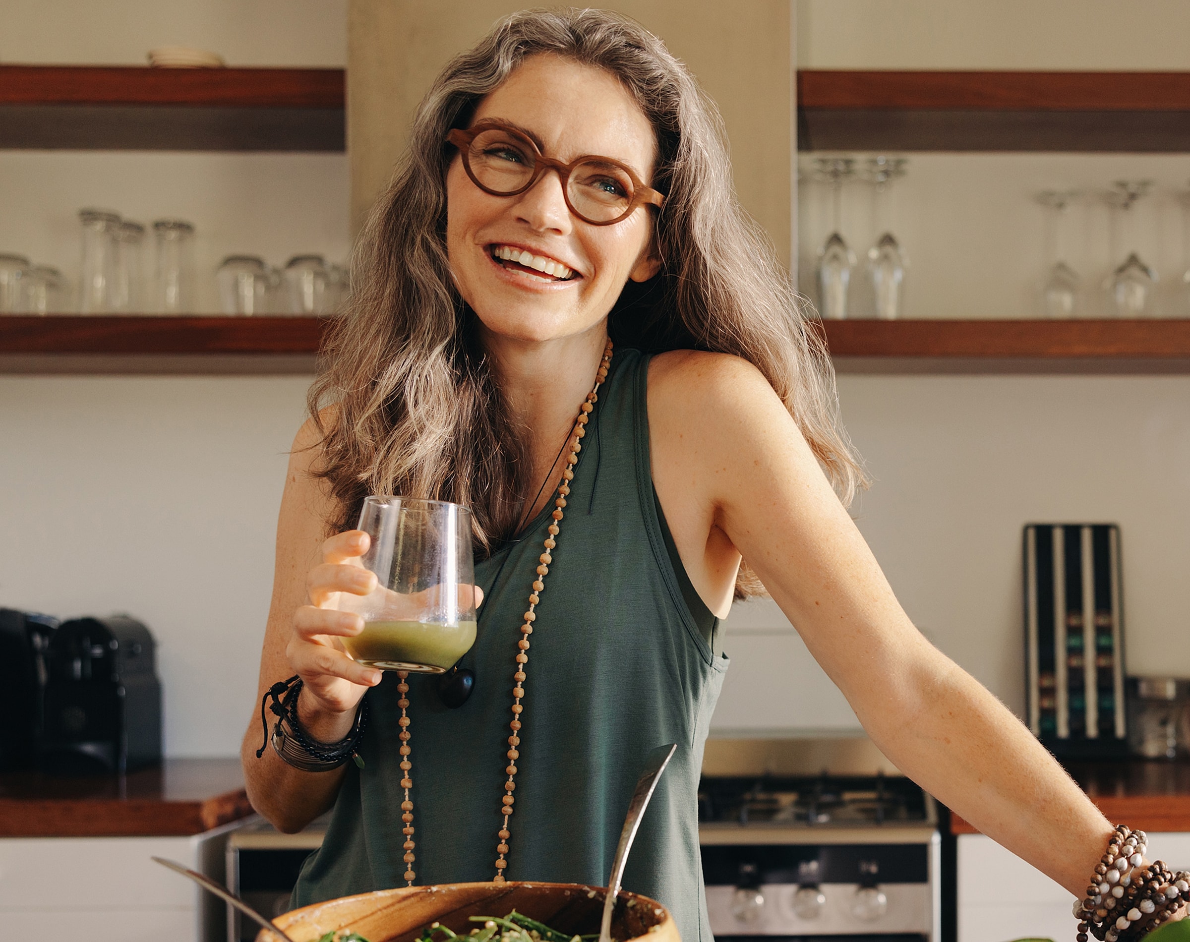 Woman smiling with drink in modern kitchen.